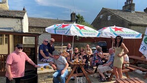 An outdoor gathering with people seated at wooden tables under Heineken Silver umbrellas. - The Shepherds Rest (Sowerby Bridge)