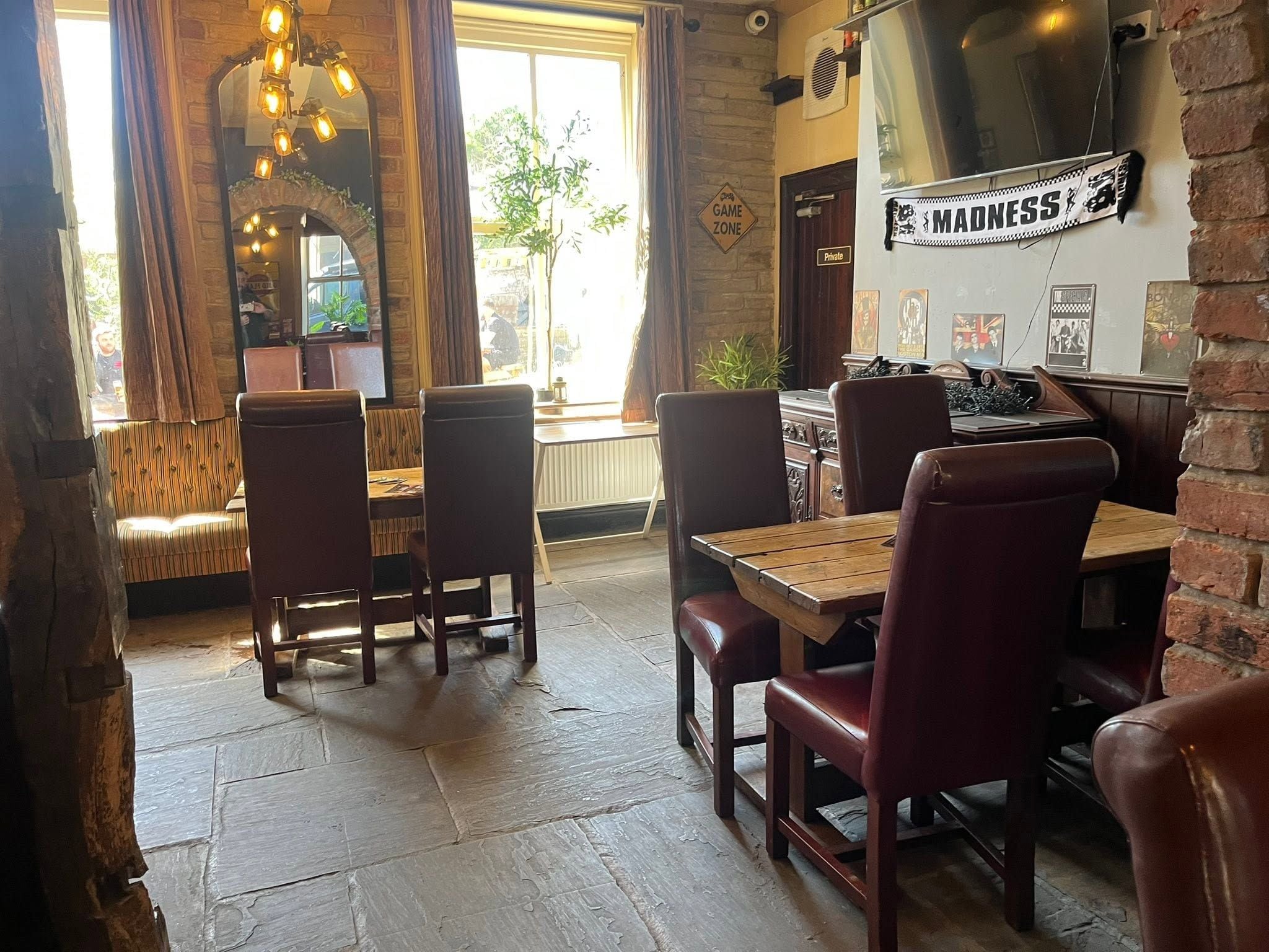Een restaurantinterieur met bakstenen muren, houten tafels en leren stoelen.