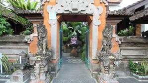 A traditional gate with two lion statues, a number '12' sign, and a pathway leading to a building. - Capital O 94011 Binhari Guest House (Ubud)