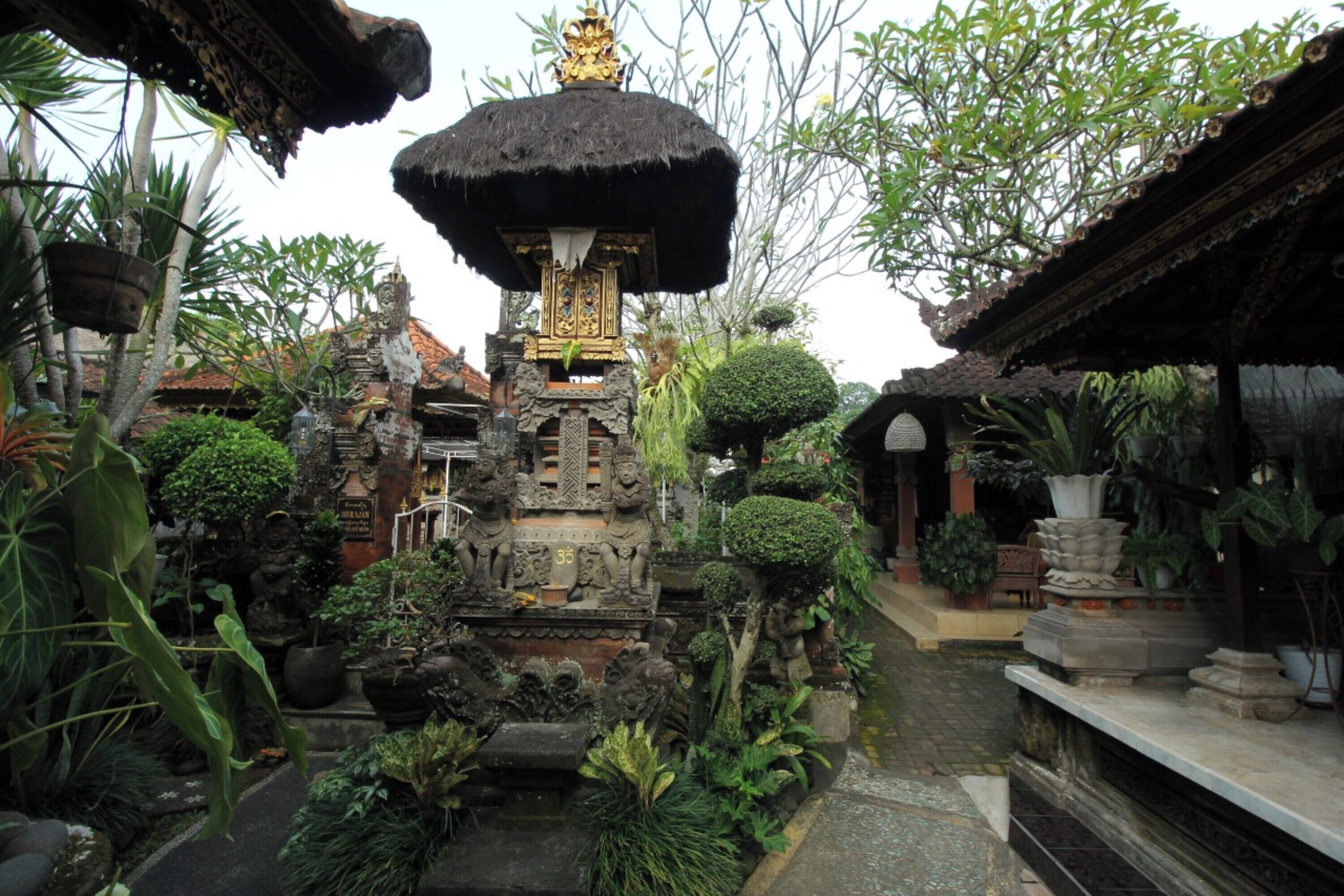 A traditional Balinese temple with intricate carvings, a central shrine, and lush tropical vegetation.