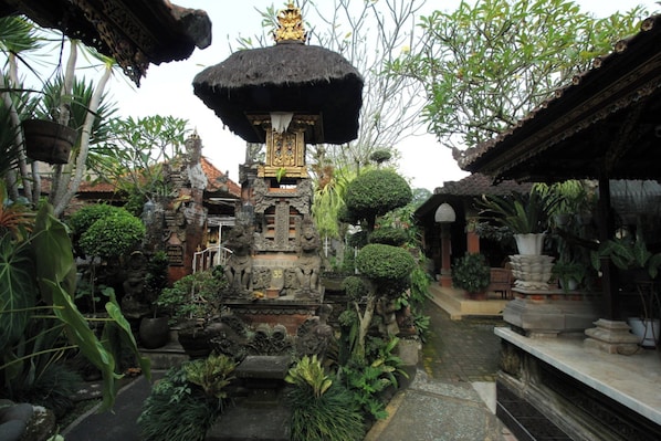 A traditional Balinese temple with intricate carvings, a central shrine, and lush tropical vegetation. - Capital O 94011 Binhari Guest House (Ubud)