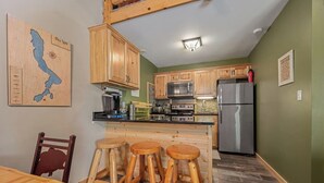 Una cocina con armarios de madera, un refrigerador de acero inoxidable y una isla de madera con taburetes.