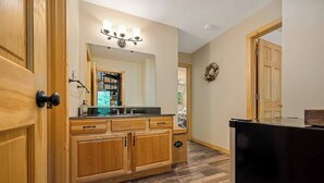 Un baño con muebles de madera, un espejo, un lavabo y un perchero para toallas.
