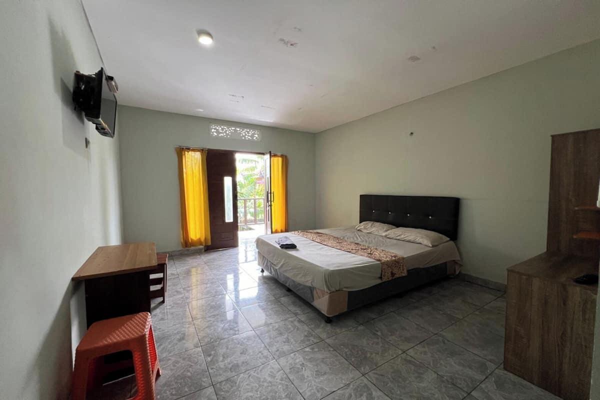 A bedroom with a bed, a desk, a chair, and a TV on the wall.
