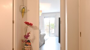 Un couloir mène à une chambre à coucher où se trouvent un lit, une porte ornée d’un motif en forme d’oiseau et une affiche accrochée au mur.