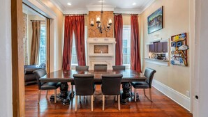 Ein Esszimmer mit Kamin, einer Chandelieber und einem Esstisch mit Stühlen.