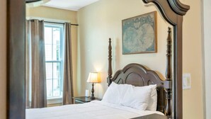Ein Hotelzimmer mit einem großen Bett, einem Nachttisch mit Lampe, einer Karte an der Wand und einem Fenster mit Vorhängen.