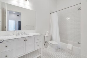 A modern bathroom with a white vanity, a toilet, and a shower area.