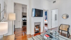 Een moderne woonkamer met houten vloeren, een glazen salontafel, een bank en een open haard.