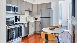 Een moderne keuken met roestvrijstalen apparatuur, een ronde eettafel en houten stoelen.