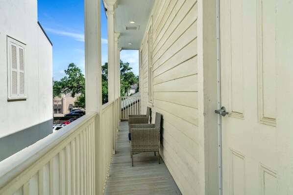 A narrow corridor with a wooden deck, white walls, and a door on the right.
