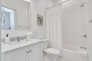 A modern bathroom with a white sink, toilet, and bathtub. - Hip & Stylish Magazine St. Apt | Balcony & Parking (New Orleans)