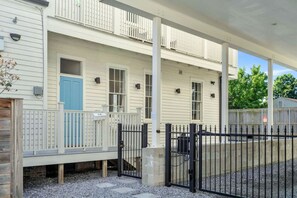 A two-story building with a covered porch, a blue door, and a black gate.