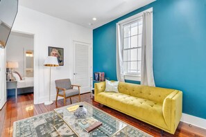 A living room with a yellow sofa, a glass coffee table, a lamp, and a blue wall.