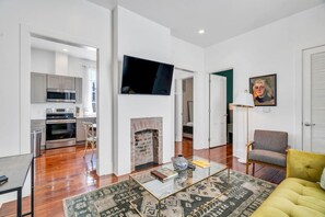 A modern living room with a fireplace, a flat-screen TV, and a yellow sofa.
