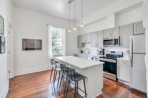 A modern kitchen with white cabinets, stainless steel appliances, and a large island with bar stools.