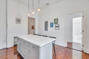 A spacious kitchen with a large island, wooden flooring, and pendant lighting.