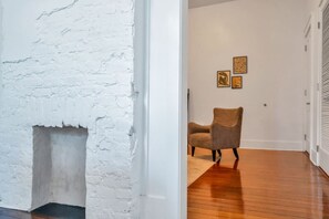 A room with a white brick wall, a wooden floor, and a chair.