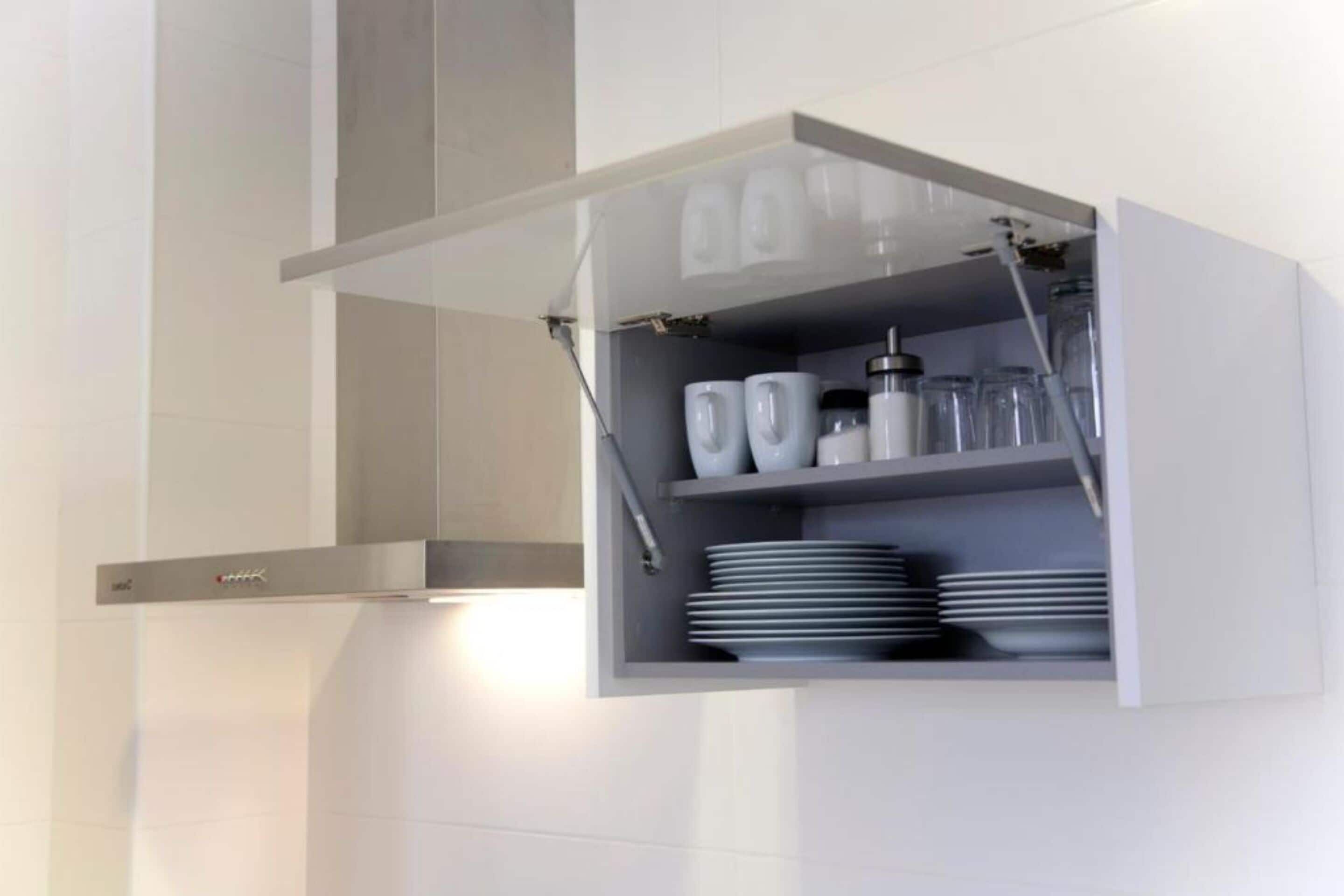 A kitchen with a built-in cabinet containing white cups, plates, and a coffee maker.