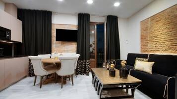 Ein modernes Wohnzimmer mit einem schwarzen Sofa, einem Holztisch und einem Essbereich mit weißen Stühlen.