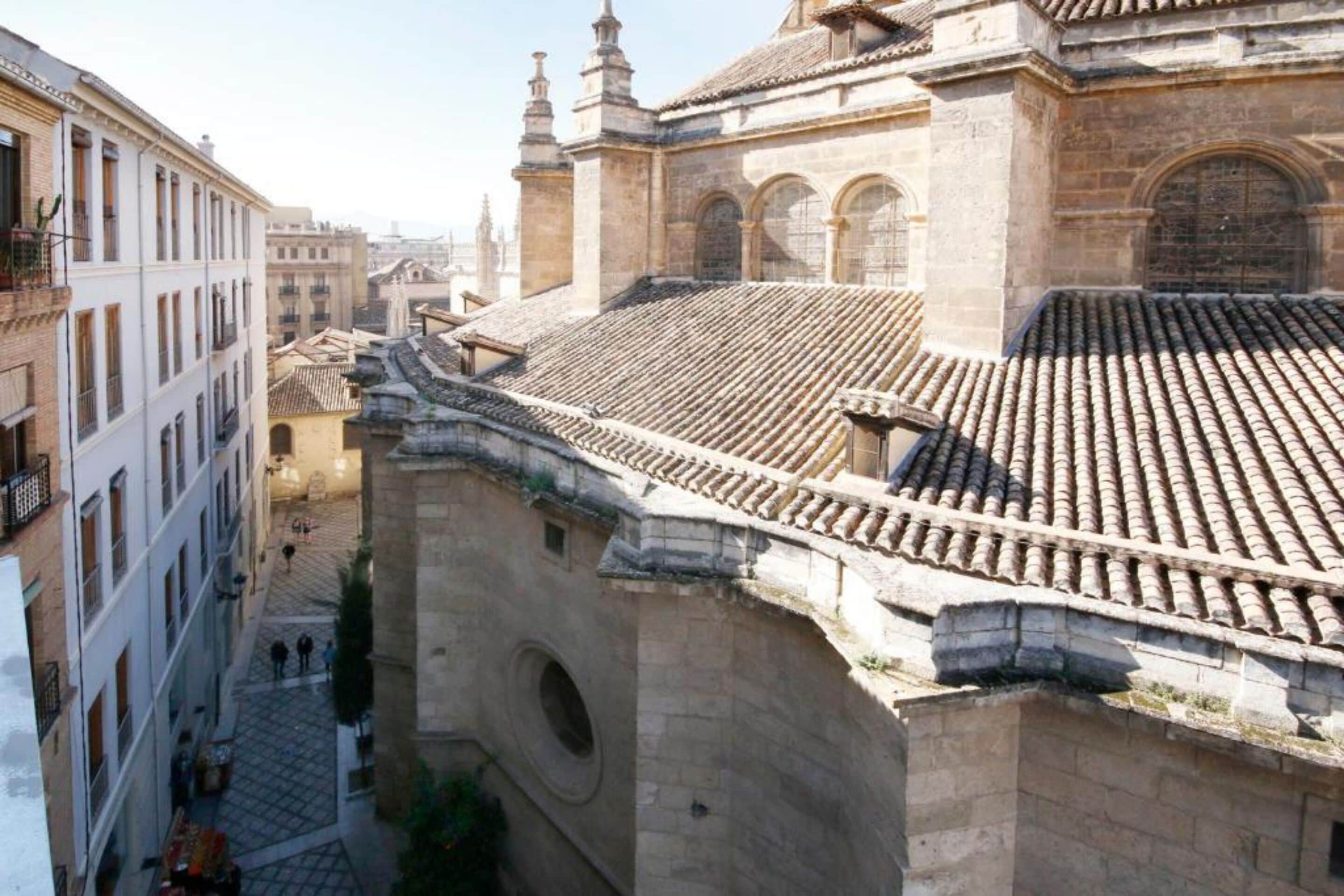 A historic building with a tiled roof and arched windows, surrounded by other buildings.