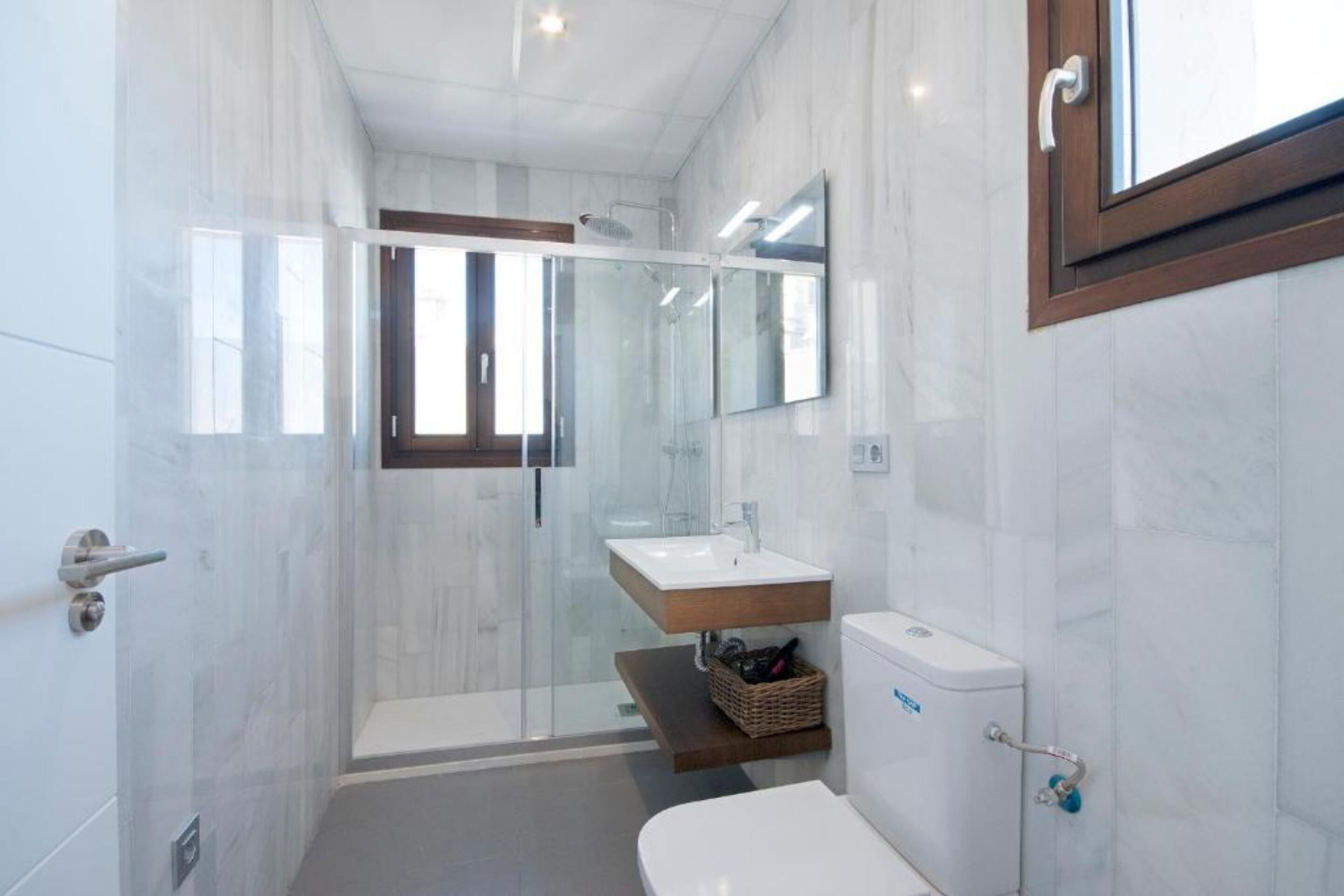 A modern bathroom with a glass-enclosed shower, a white sink, and a toilet.