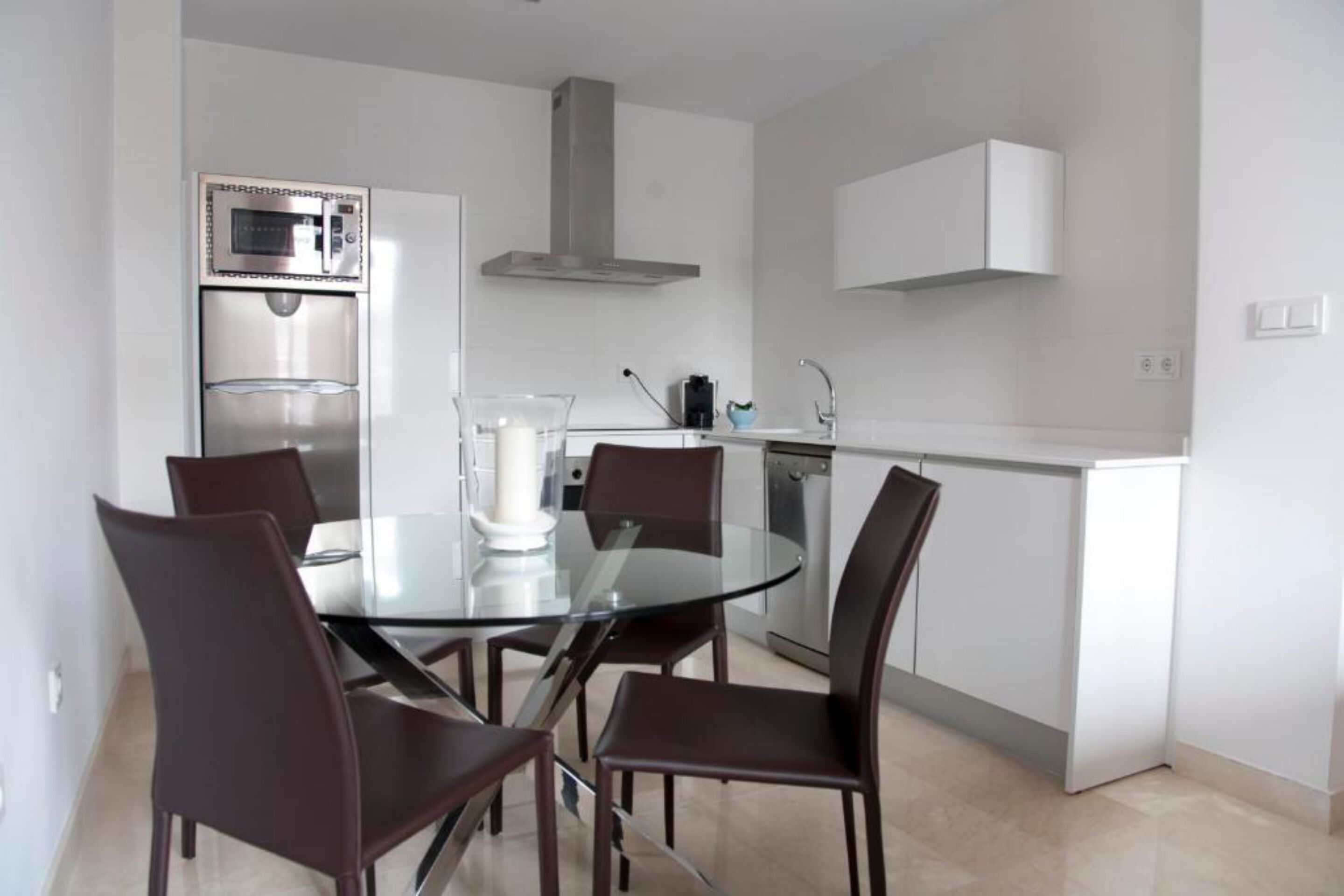A modern kitchen with a built-in microwave, a stainless steel refrigerator, and a white cabinet above the sink.
