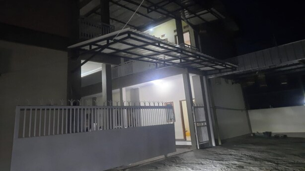 Un edificio de varios niveles con balcón y entrada protegida por un portón.