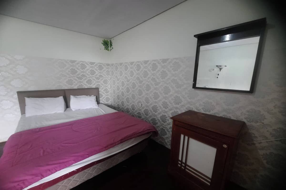 Une chambre à coucher comprenant un lit, une table de chevet, un miroir fixé au mur et un papier peint à motifs.