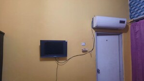 Una habitación con televisor de pared, aire acondicionado y una puerta con rejilla.