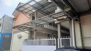 Un edificio de varios pisos con un balcón cubierto, una entrada con portones y un equipo de aire acondicionado.