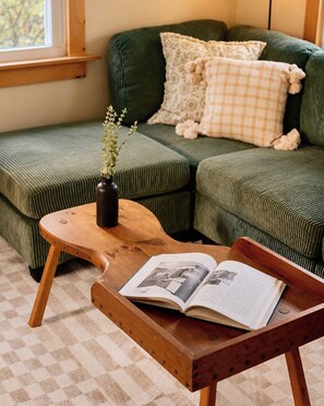 Una sala de estar acogedora con un sofá verde, una mesita de madera y un libro.