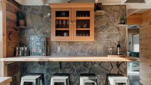A kitchen with a stone wall, wooden cabinets, and bar stools.