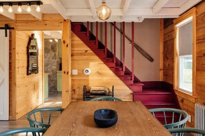 Ein Holzinnenraum mit Treppe, Esstisch und Stühlen.
