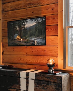 Eine Holzwand mit einem gerahmten Bild von einem Zelt an einem Fluss, einem Globus auf einem Tisch und einem Fenster mit Blick.
