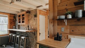 A kitchen with wooden walls, a stone accent wall, and a bar area with stools.