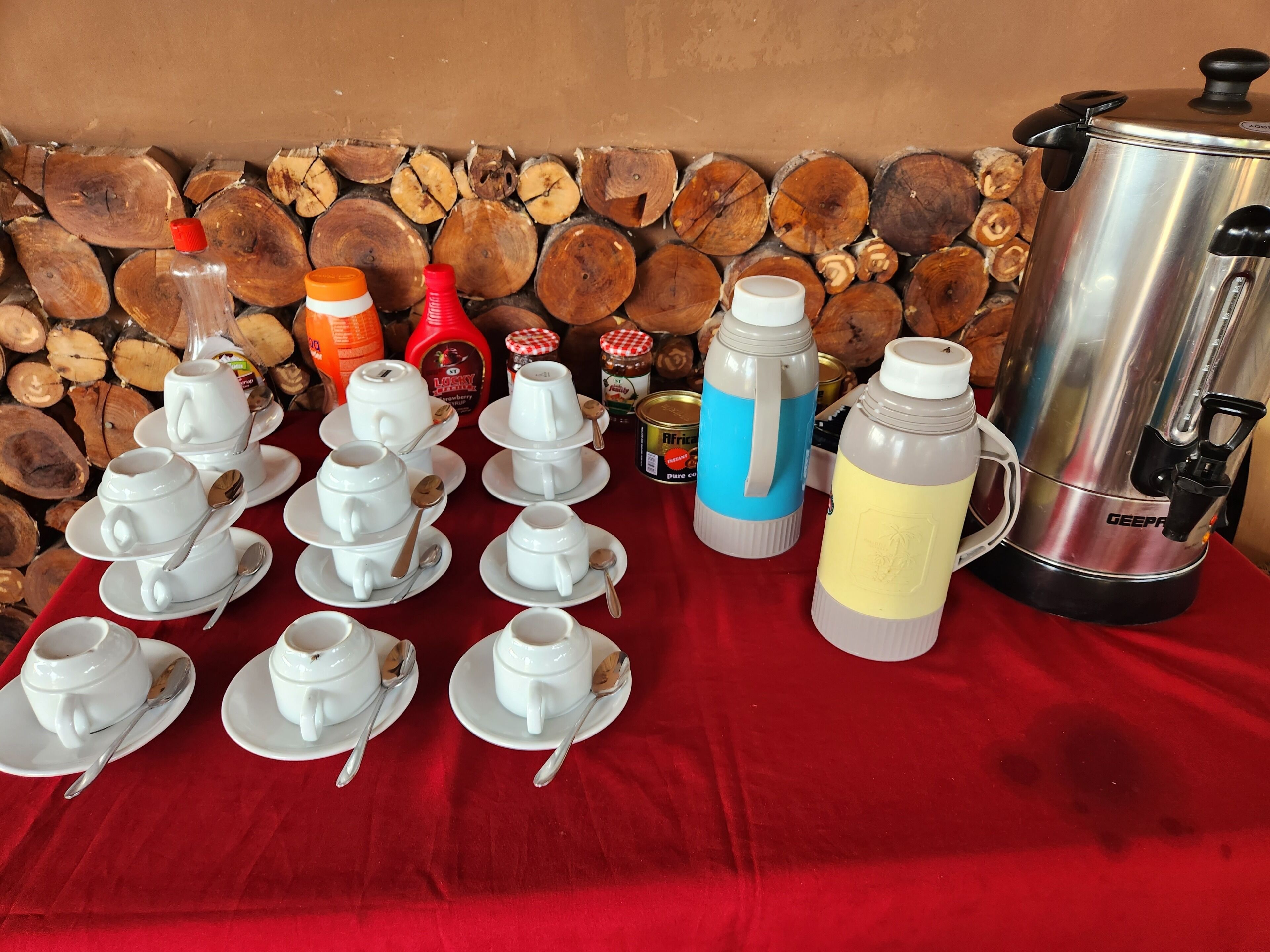 A table with multiple coffee cups and spoons, a water bottle, and a coffee pot.