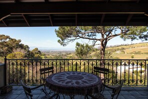 Enjoy a serene outdoor space with a round table and four chairs, overlooking rolling hills and a distant body of water.