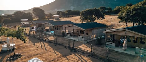 Une propriété rurale comprenant plusieurs chalets en bois, un espace clôturé et un chemin de terre.