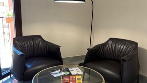 A modern room with two leather chairs, a glass coffee table, and a floor lamp. - Calua Luxury Rooms (Agrigento)