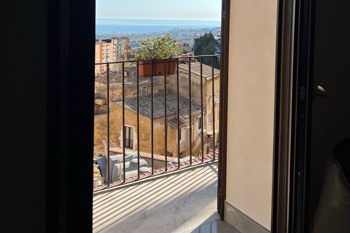 A balcony with a view of a cityscape and the sea.