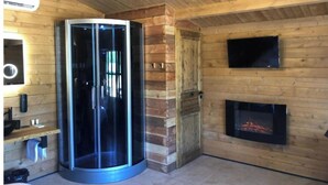 A modern interior with a glass elevator, a fireplace, and wooden walls.
