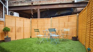 A fenced backyard with artificial grass, a table, and four chairs. - The Green Garden House -Stunning large house near Shopping centre, Finsbury Park (Greater London)