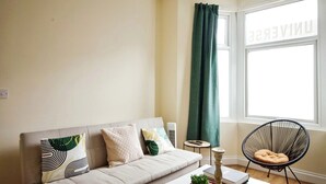 A living room with a sofa, a chair, a coffee table, and a window with curtains. - The Green Garden House -Stunning large house near Shopping centre, Finsbury Park (Greater London)