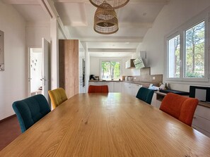 Eine moderne Küche mit weißen Schränken, einem Holzespeisetisch und bunten Stühlen.