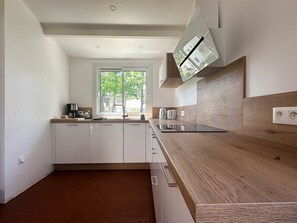 Une cuisine moderne dotée d’une grande fenêtre, d’un plan de travail en bois et de meubles blancs.