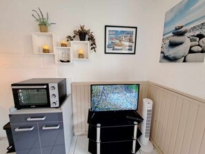 Compact living space with a kitchenette, microwave, flat-screen TV, and a cozy reading nook.