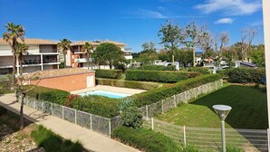 Zona residencial con piscina, jardín vallado y varios edificios con balcones.
