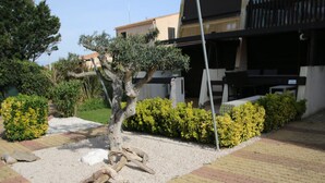 A landscaped garden with a tree, gravel, and hedges. - Charming Studio for 2 with Pool Access, Renovated, Parking, Near Beach (Cap d'Agde naturisme)
