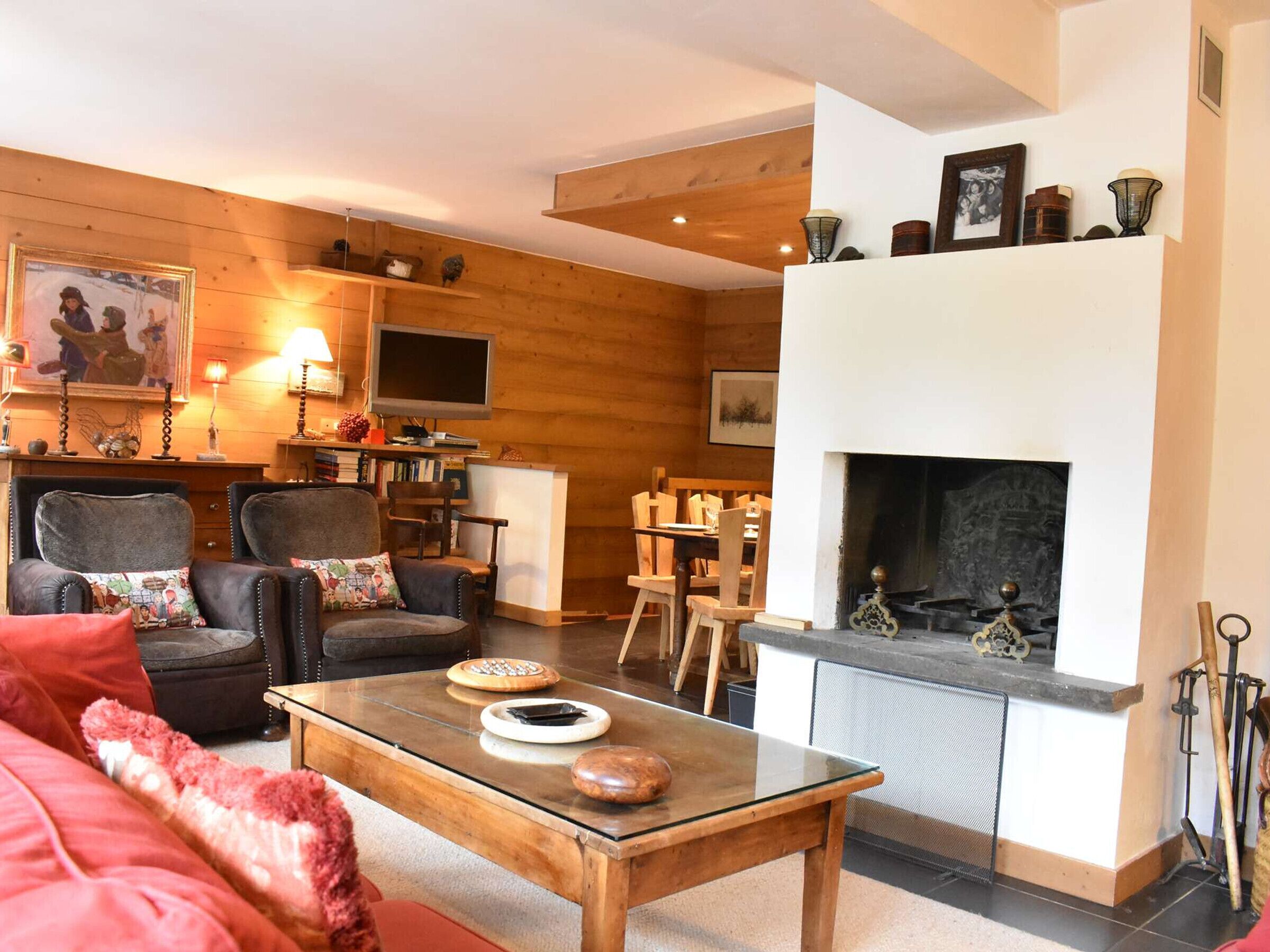 Una sala acogedora con chimenea, paredes de madera, televisor y comedor.